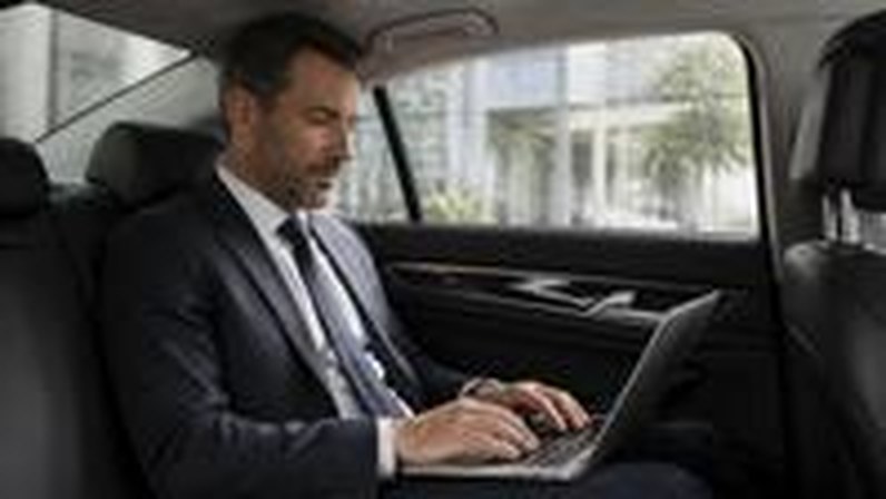 Executive working on a laptop in a corporate sedan